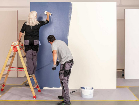 Maler und Malerin tragen CD DecoGrund in der Farbe 3D Saphir 40 deckend auf und glätten die Oberfläche mit einer Venezianerkelle nach